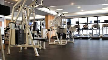 Ein Fitnessstudio mit verschiedenen Trainingsgeräten, großen Fenstern und einem klaren, modernen Design.