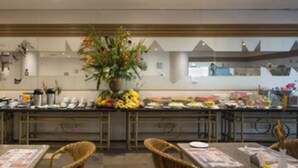 A buffet area with a variety of food items and a central floral arrangement. - Hotel Resort Rio Poty (São Luís)