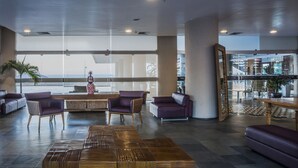 A spacious lobby with leather sofas, a central coffee table, and large windows offering a view of the water. - Hotel Resort Rio Poty (São Luís)