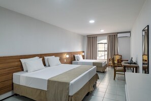 A hotel room with two beds, a desk, a chair, and an air conditioning unit.