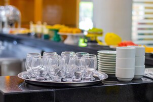 Una mesa de buffet con vasos transparentes y platos apilados en una bandeja.