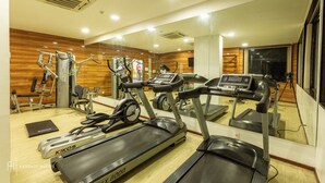 Un gimnasio con cintas de correr, elípticas y equipo de pesas.