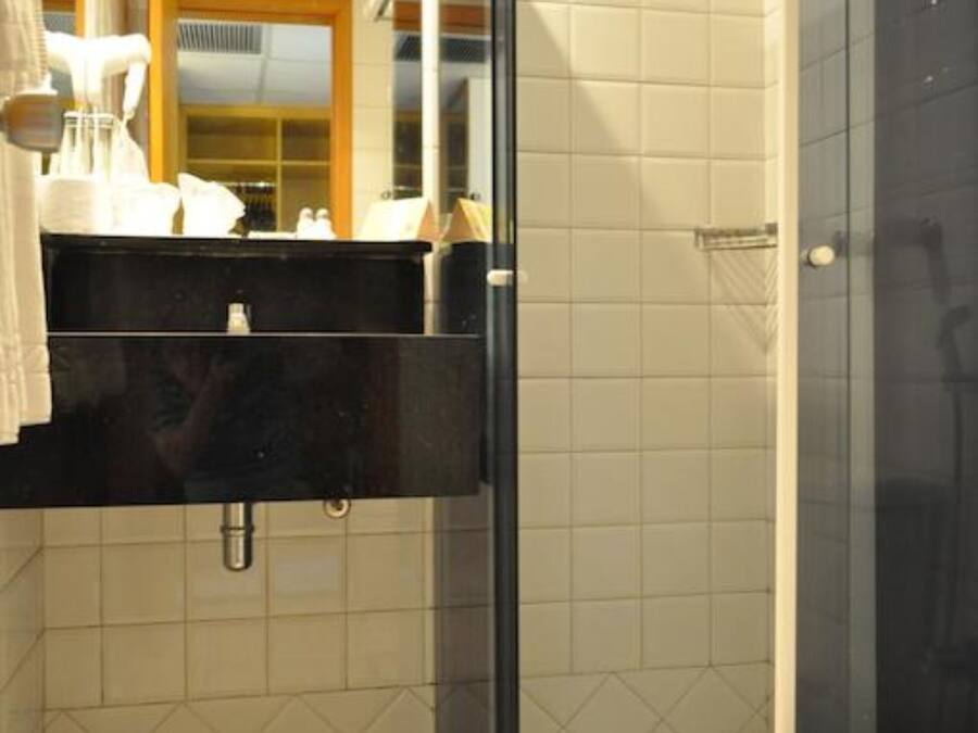 Un baño moderno con cabina de ducha de vidrio, lavamanos negro y un inodoro.