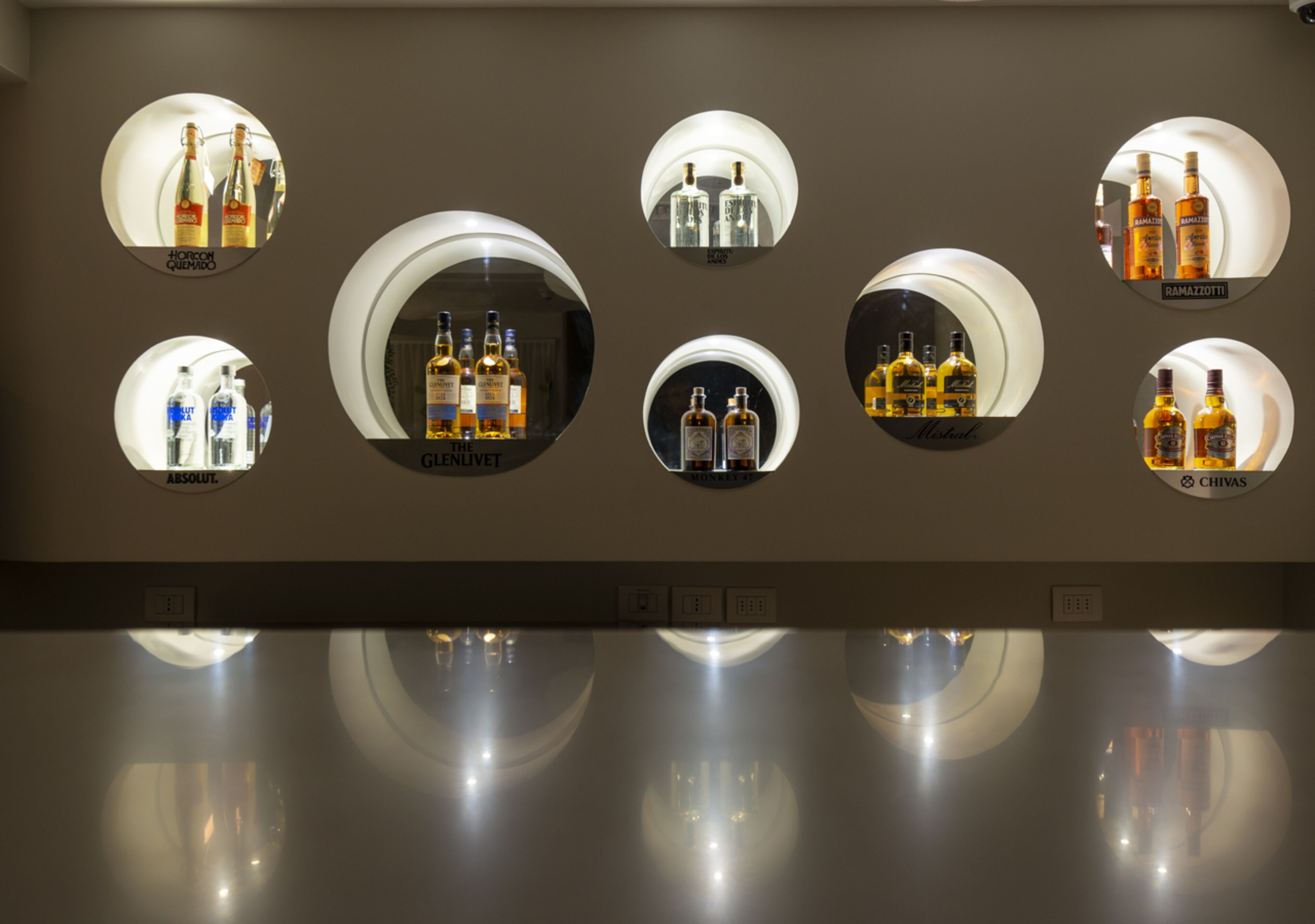 A wall with circular mirrors displaying various liquor bottles.