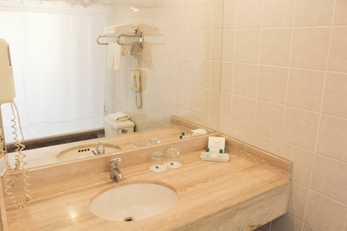 A bathroom with a sink, mirror, towel rack, and a telephone.