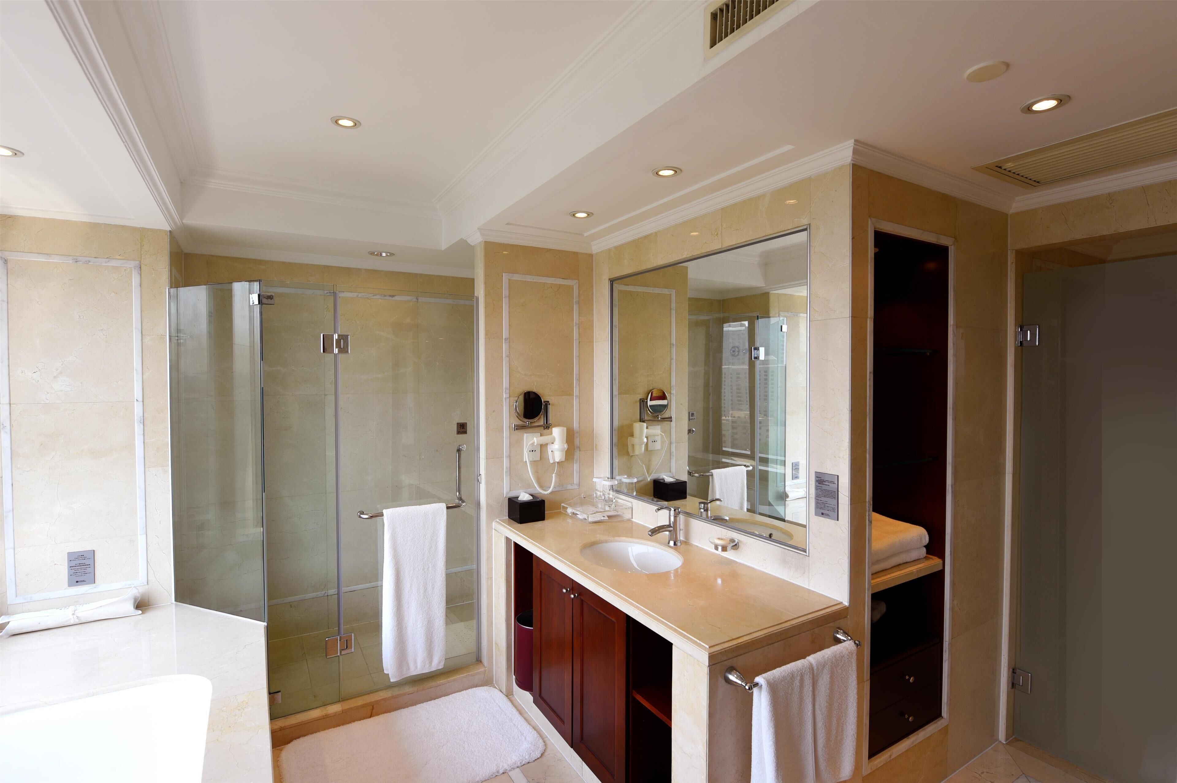 Une salle de bain moderne avec une douche à parois de verre, un grand miroir et un meuble-lavabo.