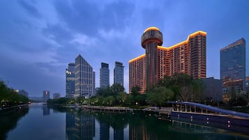 A cityscape with modern high-rise buildings, a calm river, and a bridge.