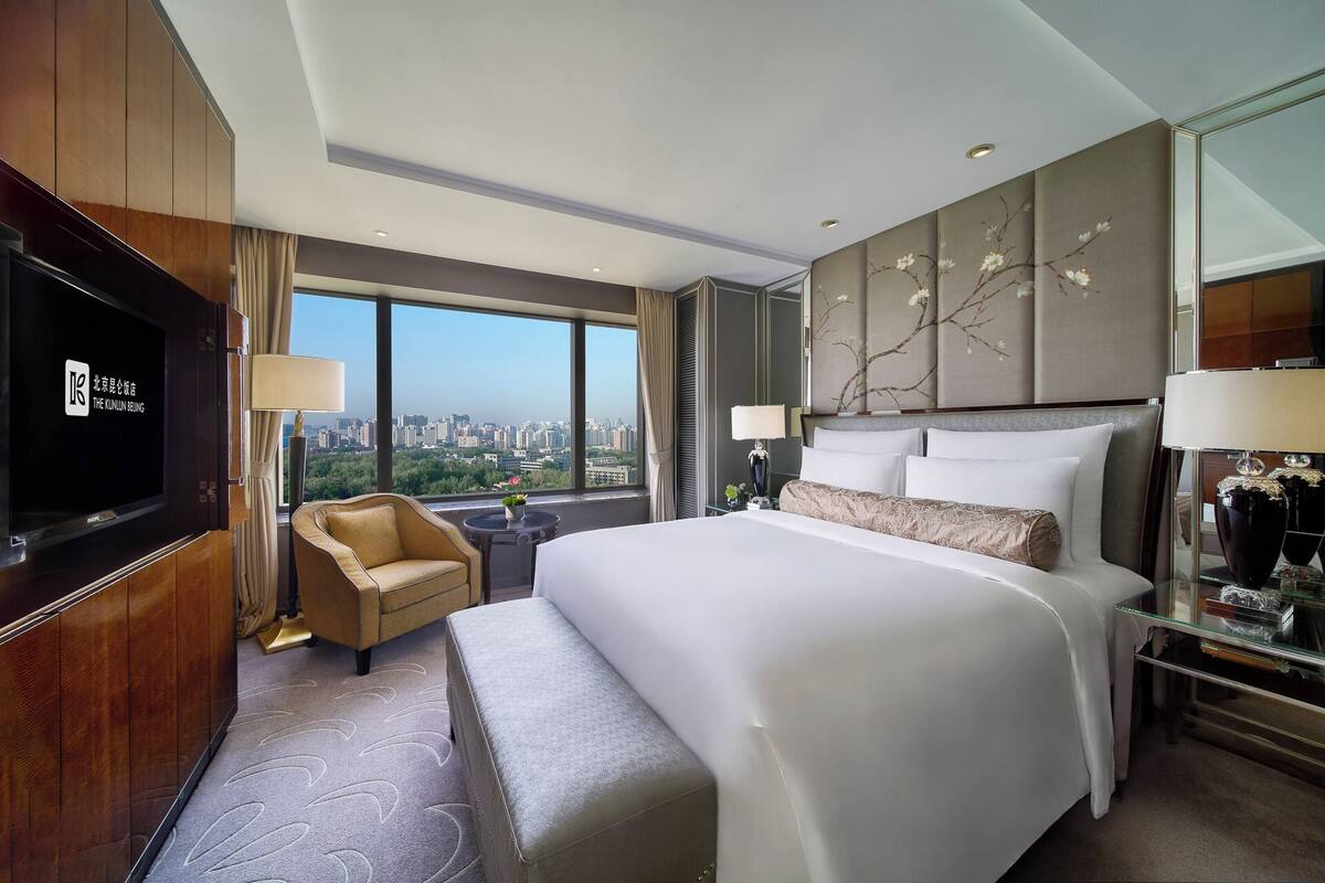 Una habitación de hotel con una cama grande, televisión, sofá y vistas a la ciudad.