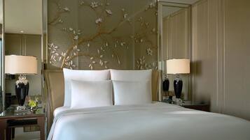 Una habitación de hotel con una cama grande, dos mesitas de noche con lámparas, un panel decorativo y un espejo.