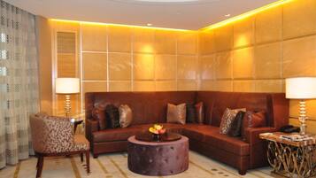 Un salón moderno con un sofá de cuero marrón, un sillón estampado y una mesa de centro redonda.