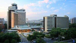 Un moderno complejo hotelero con varias edificaciones, que incluye una torre distintiva y un amplio estacionamiento.