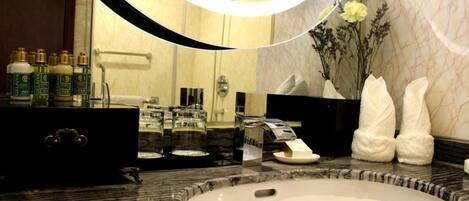 A bathroom with a marble sink, a large mirror, toiletries, and towels.
