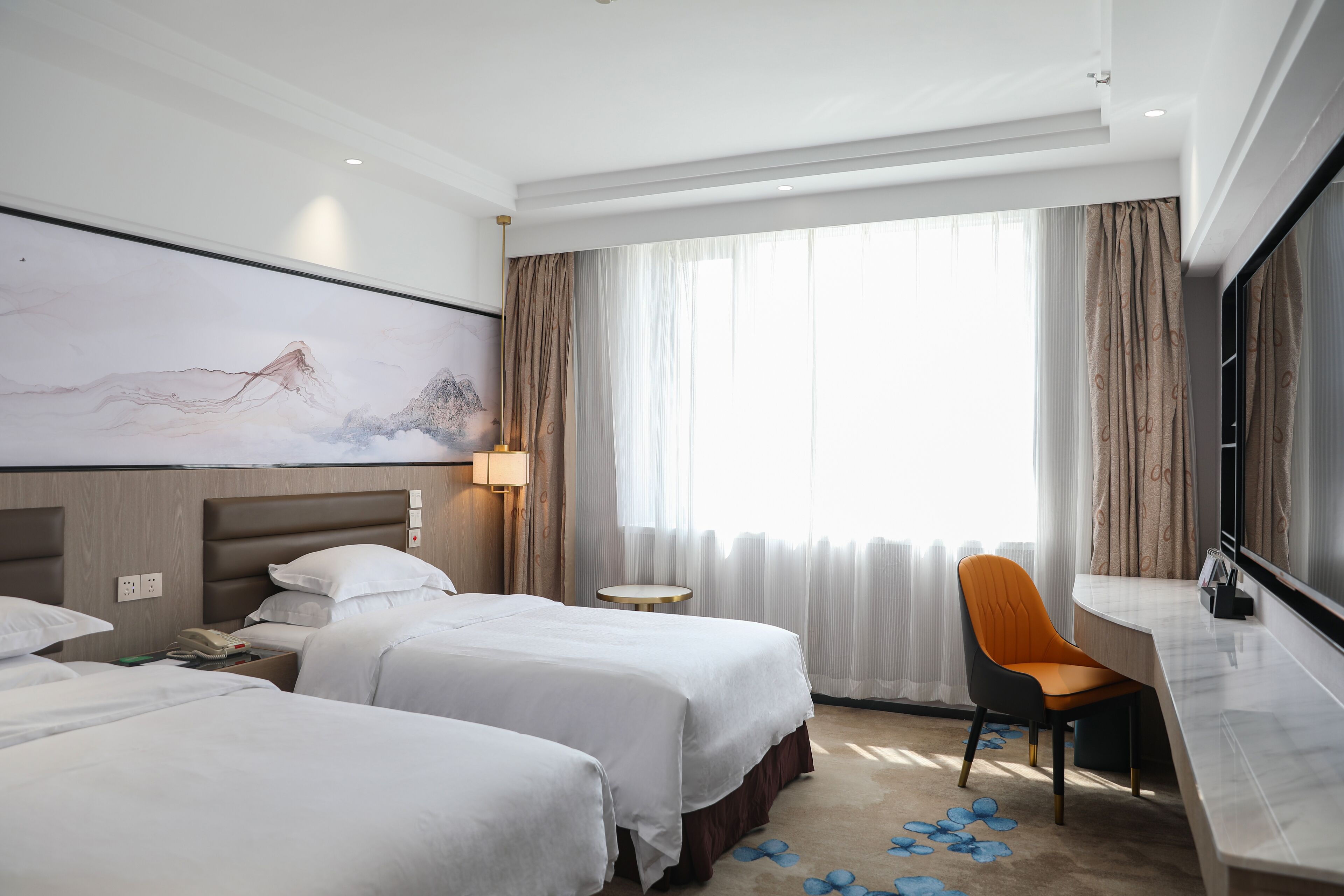A hotel room with two beds, a desk, a chair, a TV, and a painting on the wall.