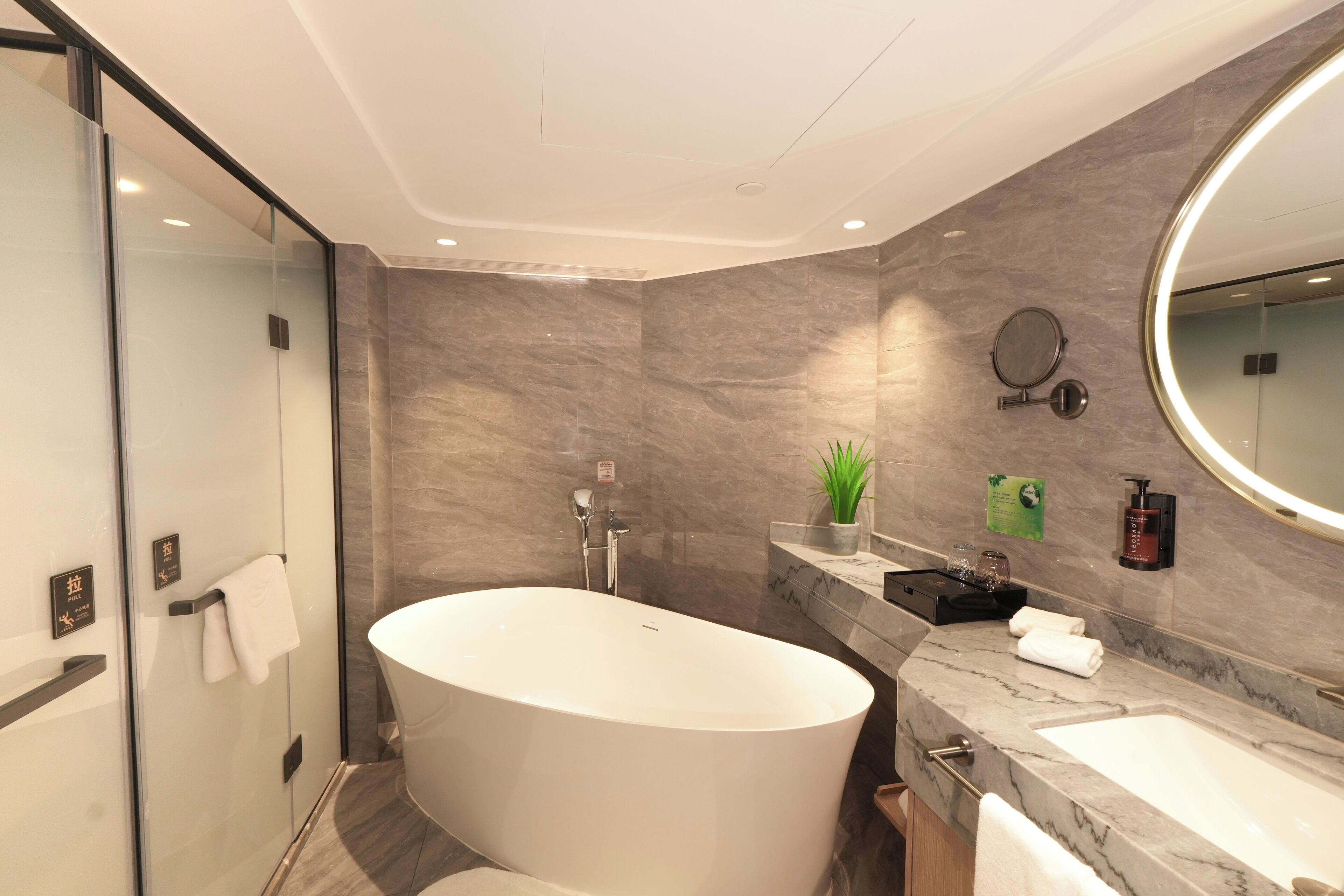 A modern bathroom with a freestanding bathtub, a large mirror, and a marble countertop.