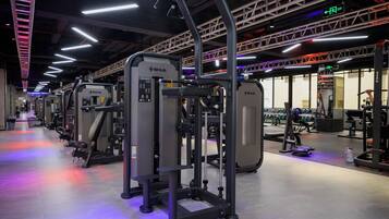 A gym with various exercise machines, including a squat rack and a chest press machine.