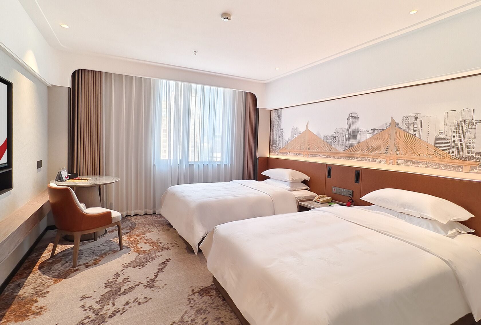 A hotel room with two beds, a small table, a chair, a cityscape mural, and a window with curtains.