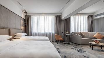 Una habitación de hotel con dos camas, un sofá, una mesita y una silla.