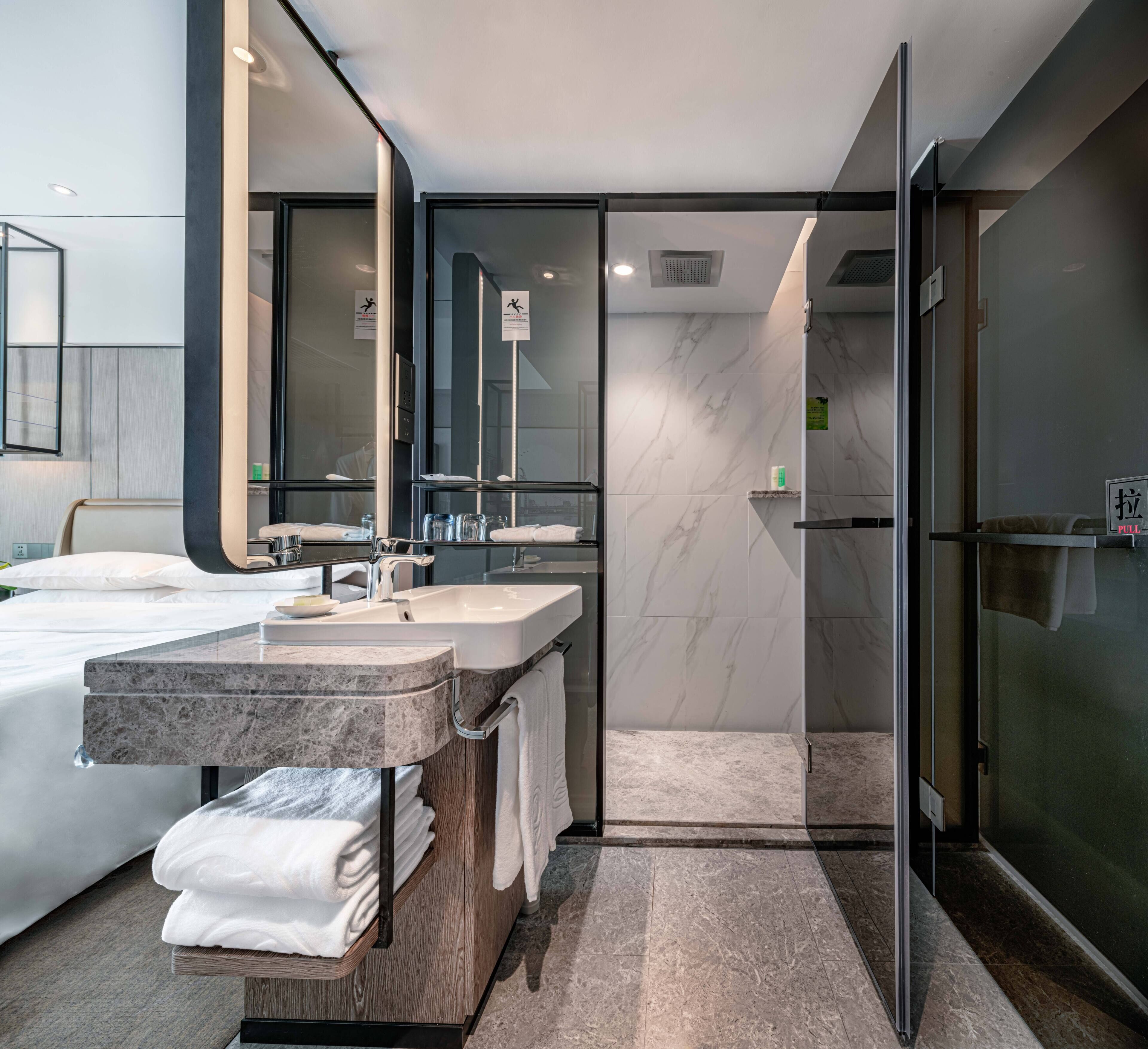 A modern bathroom with a large mirror, dual sinks, and a glass shower enclosure.