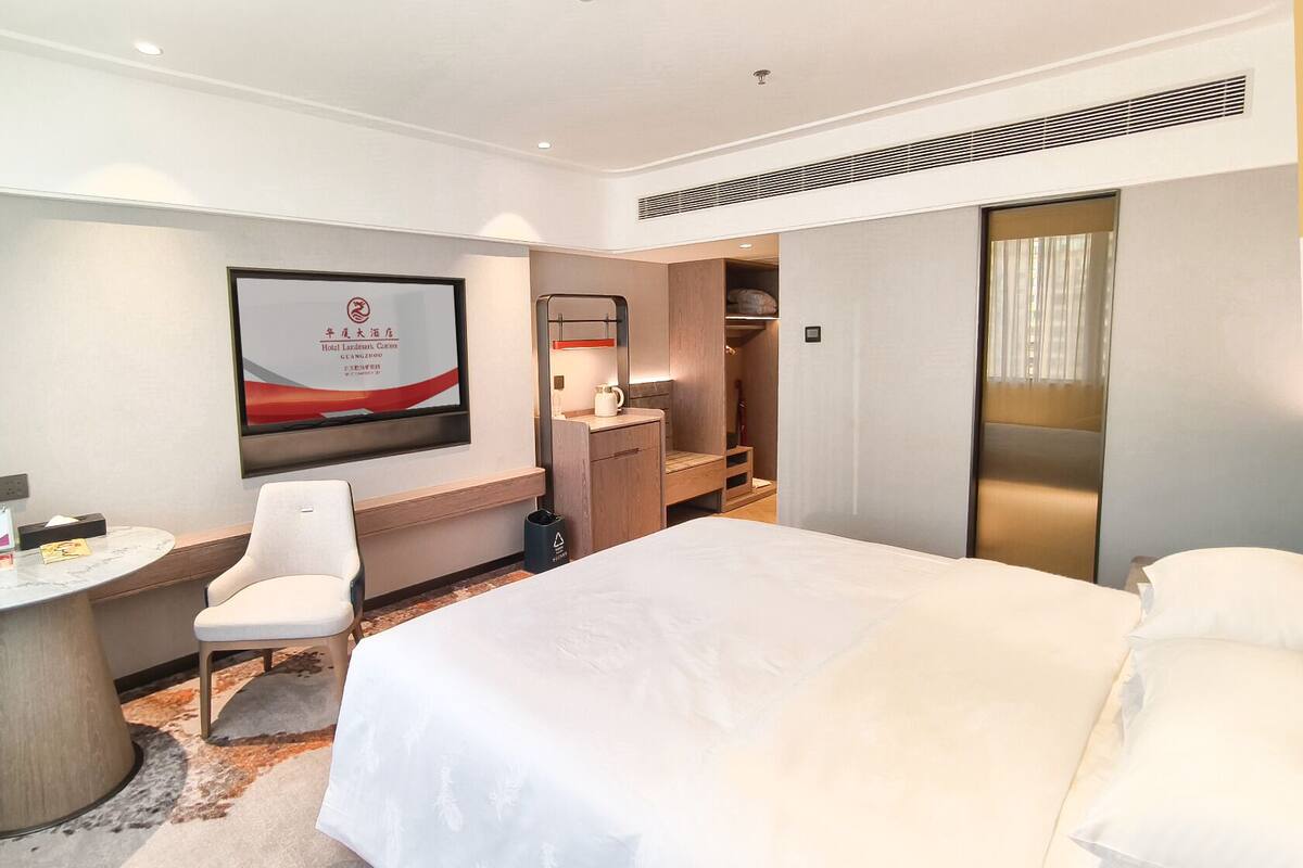 A hotel room with a bed, a desk, a chair, a wardrobe, and a bathroom.