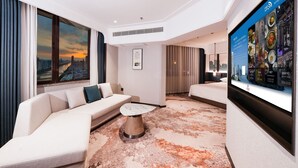 Camera d'albergo moderna con un letto grande, una poltrona, un tavolino e vista sulla città.