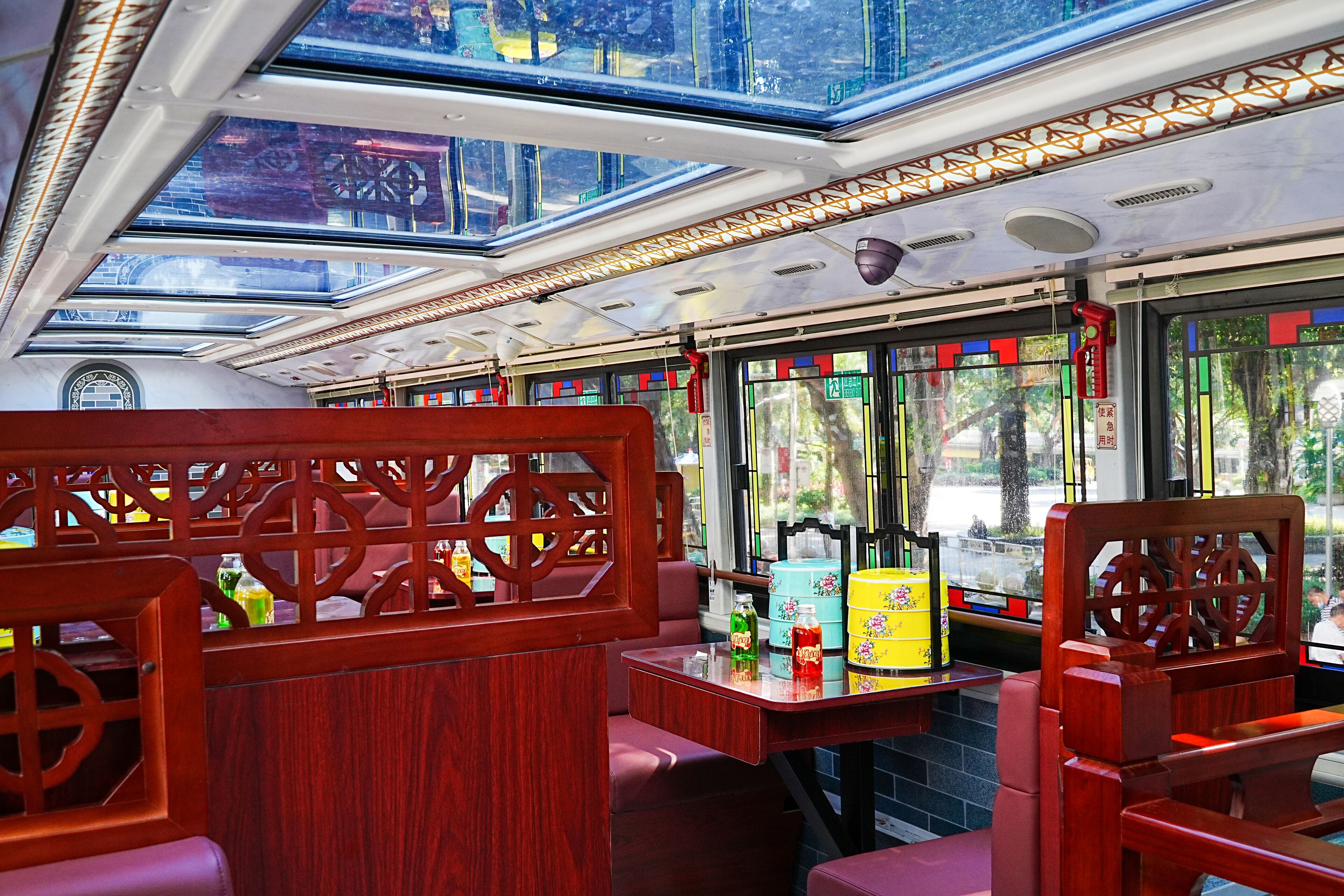 A train carriage with wooden seating, a table with beverages, and large windows.