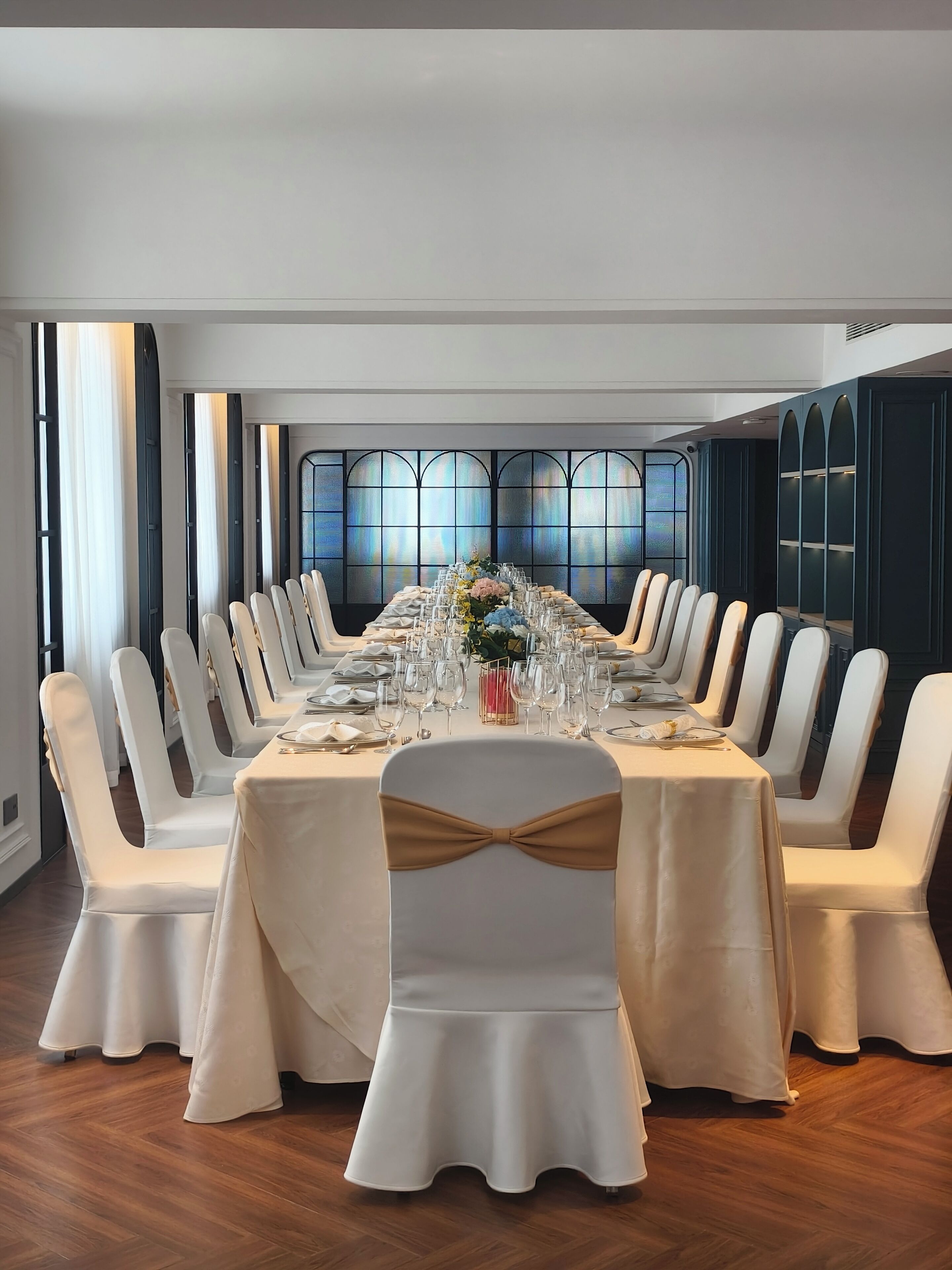A conference room with a long table, white chairs, and a large window with a view.