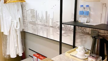 Habitación de hotel con escritorio de madera, un cuadro de un horizonte urbano, una bata colgada y una estación de café.