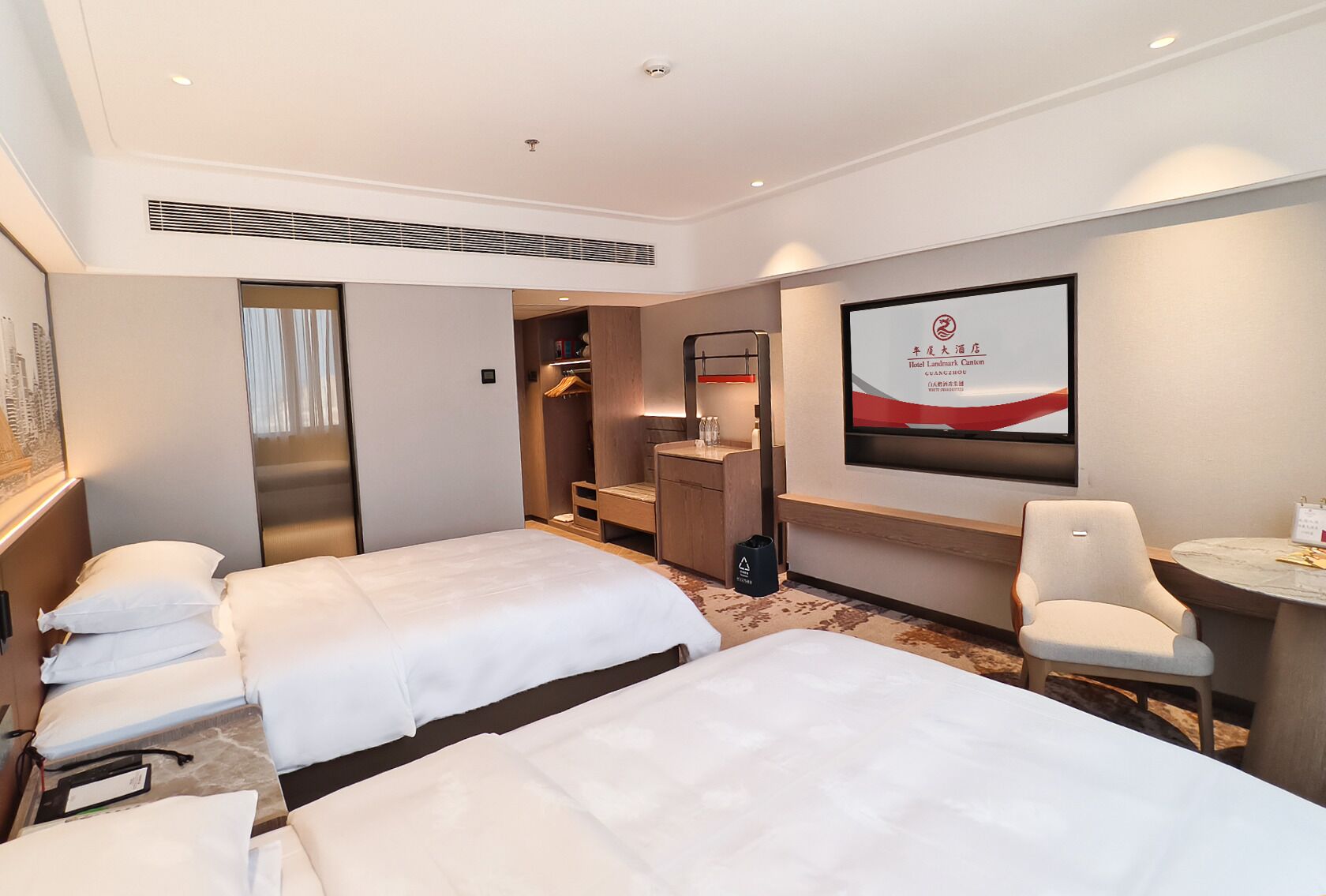 A hotel room with two beds, a desk, a chair, a TV, and a wardrobe.