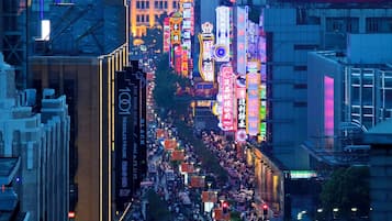 A cityscape at night with illuminated billboards and a busy street.