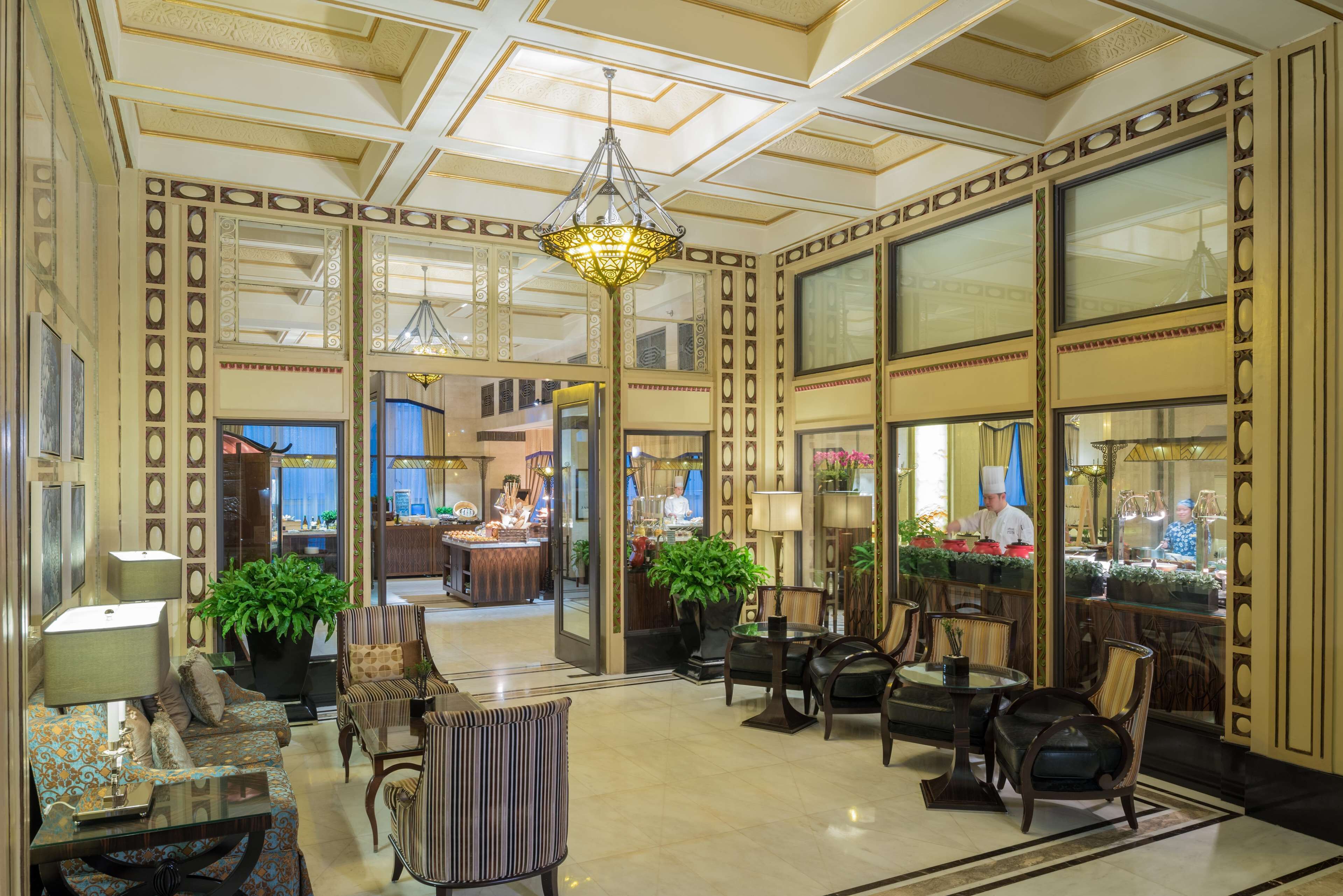 A spacious lobby with a chandelier, seating area, and a view into the restaurant.