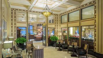 A spacious lobby with a chandelier, seating area, and a view into the restaurant.