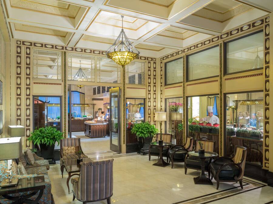 A spacious lobby with a chandelier, seating area, and a view into the restaurant.