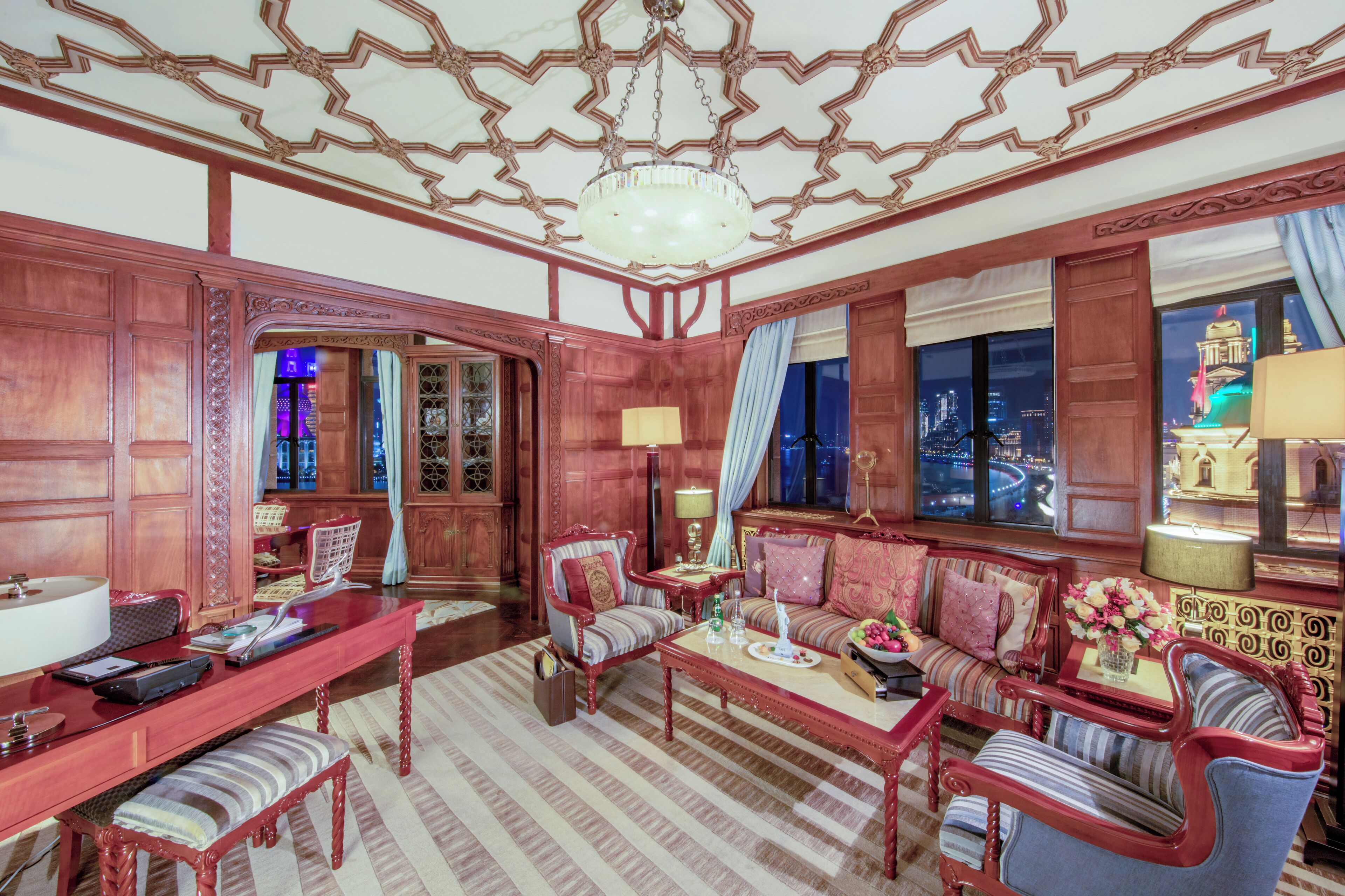 A traditional room with a wooden interior, a sofa set, a dining table, and a chandelier.