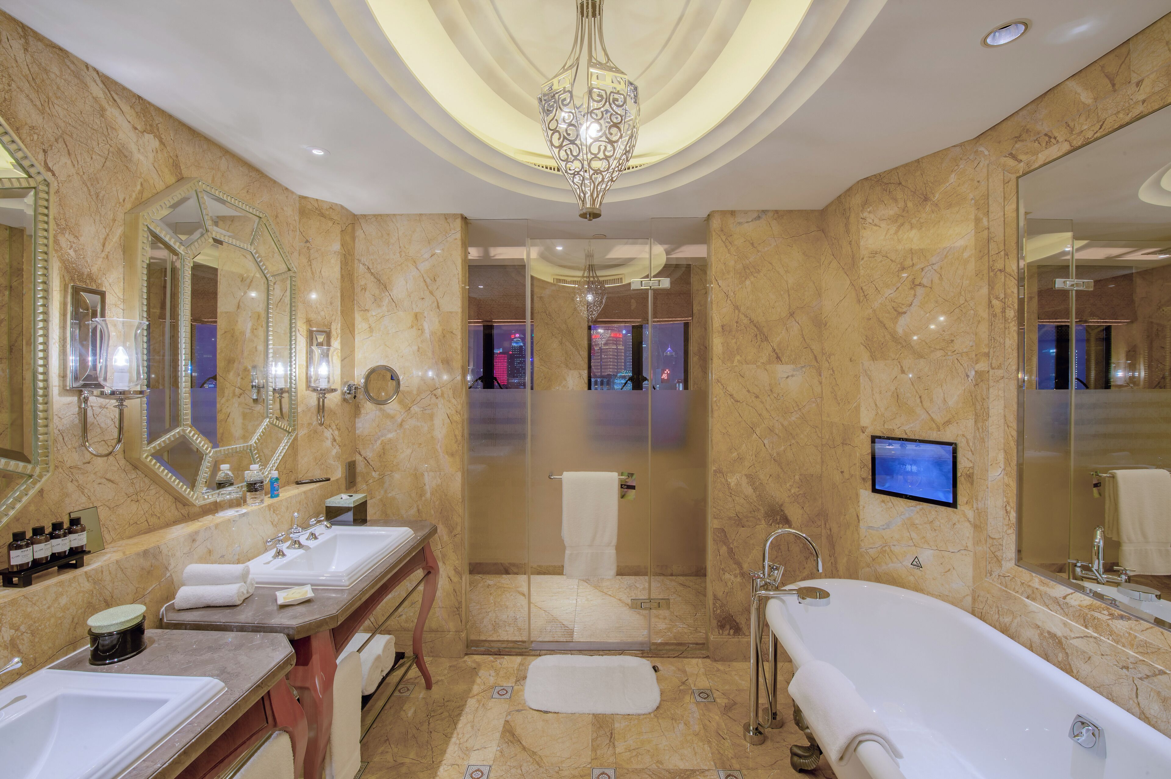 Un baño lujoso con paredes de mármol, un espejo grande, una bañera y una ducha.