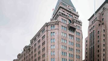 Un grand bâtiment historique, doté d’une tour d’angle imposante, de grandes fenêtres et d’une entrée centrale.