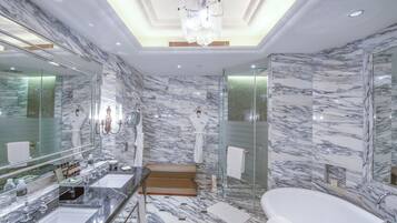A luxurious bathroom with marble walls, a large mirror, a bathtub, and a walk-in shower.