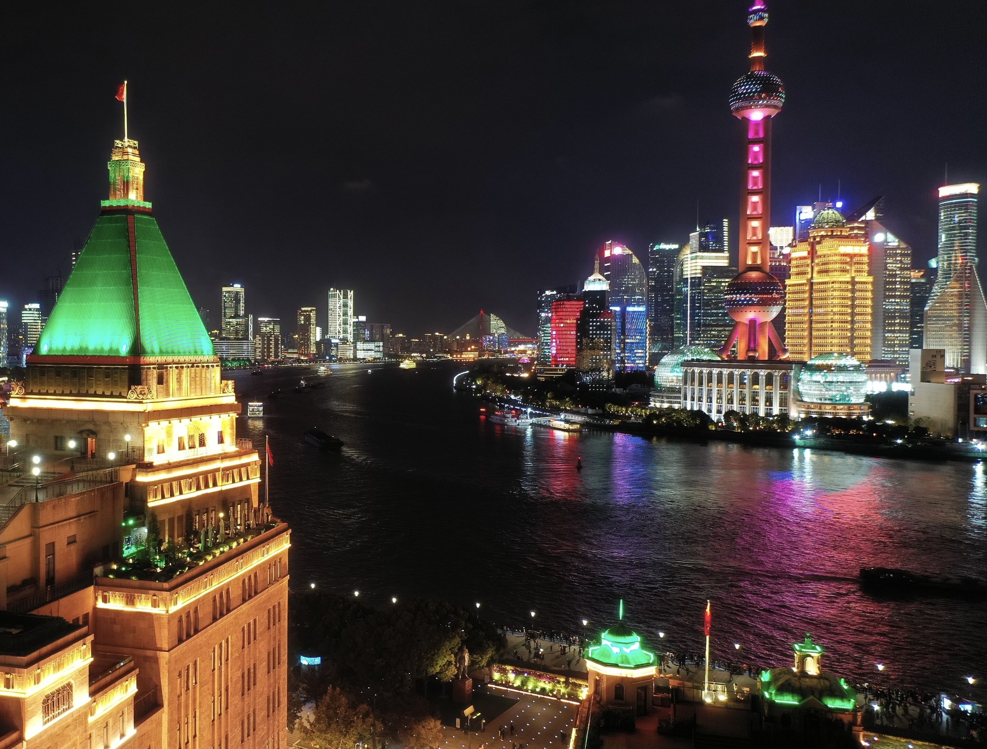 A nighttime cityscape with illuminated buildings and a river.