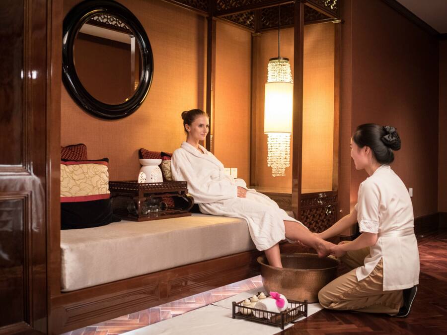Ett spa-rum med en massagebänk, en stor spegel och en traditionell lampa i asiatisk stil.