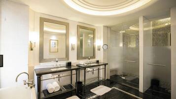 Un bagno moderno con due lavabi, uno specchio grande, una vasca e una doccia in vetro.