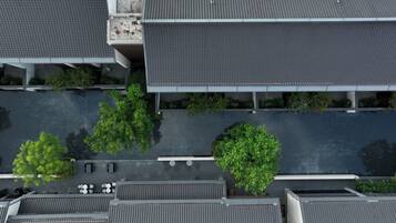 Vista aérea de un estacionamiento con árboles, una zona cubierta y un edificio de techo plano.