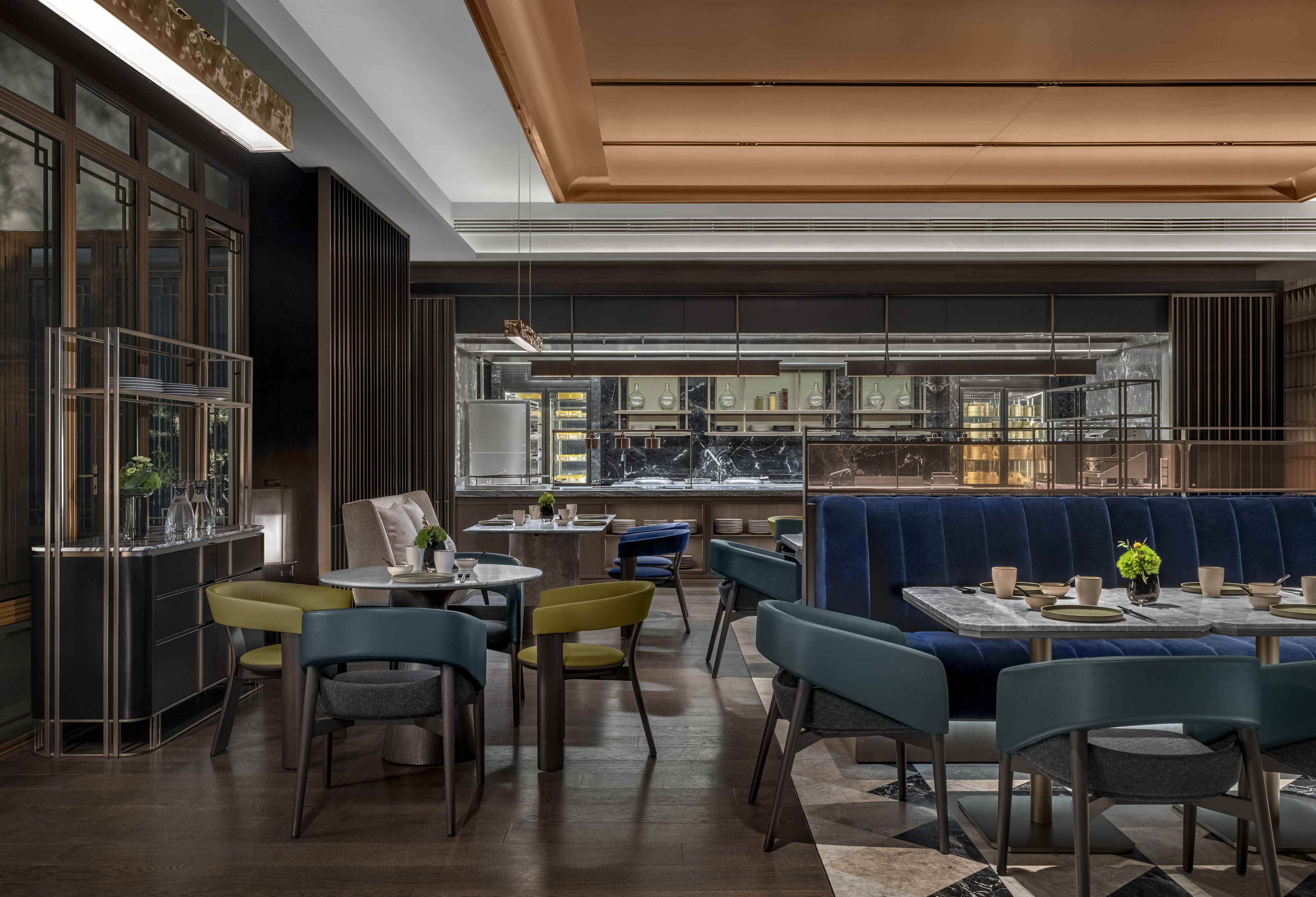 A modern restaurant with a bar area, seating with blue and yellow chairs, and a marble counter.