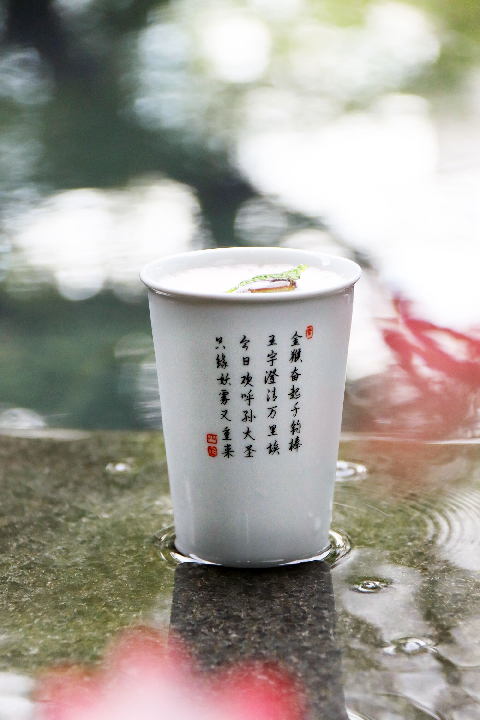 A white cup with Chinese characters on a wet surface, likely outdoors.