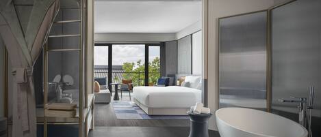 Una habitación de hotel moderna con una cama grande, una bañera independiente, un balcón con vistas y un armario con puerta corredera.