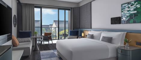 Habitación de hotel moderna con una cama grande, televisión, escritorio y balcón con vista a la ciudad.