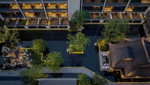 Vista aérea de un hotel con varios pisos, zonas de estar al aire libre y un patio central con fuente.