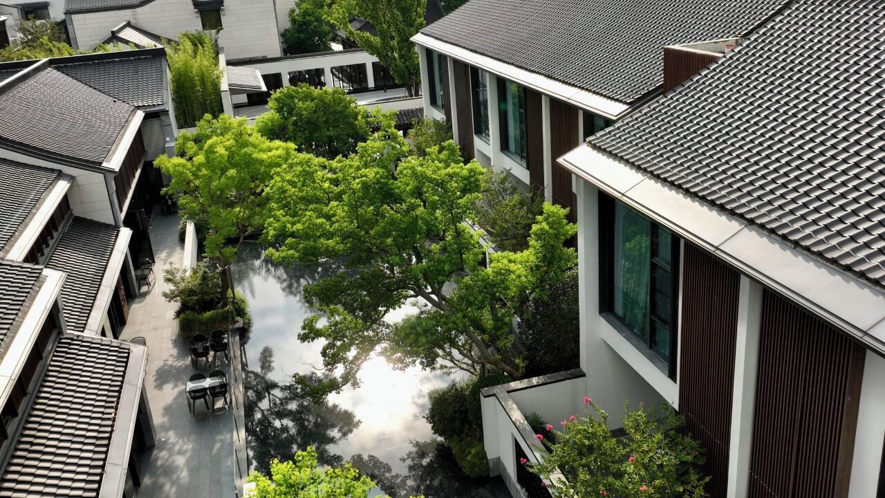 A traditional building with a modern extension, a courtyard with trees, and a water feature.
