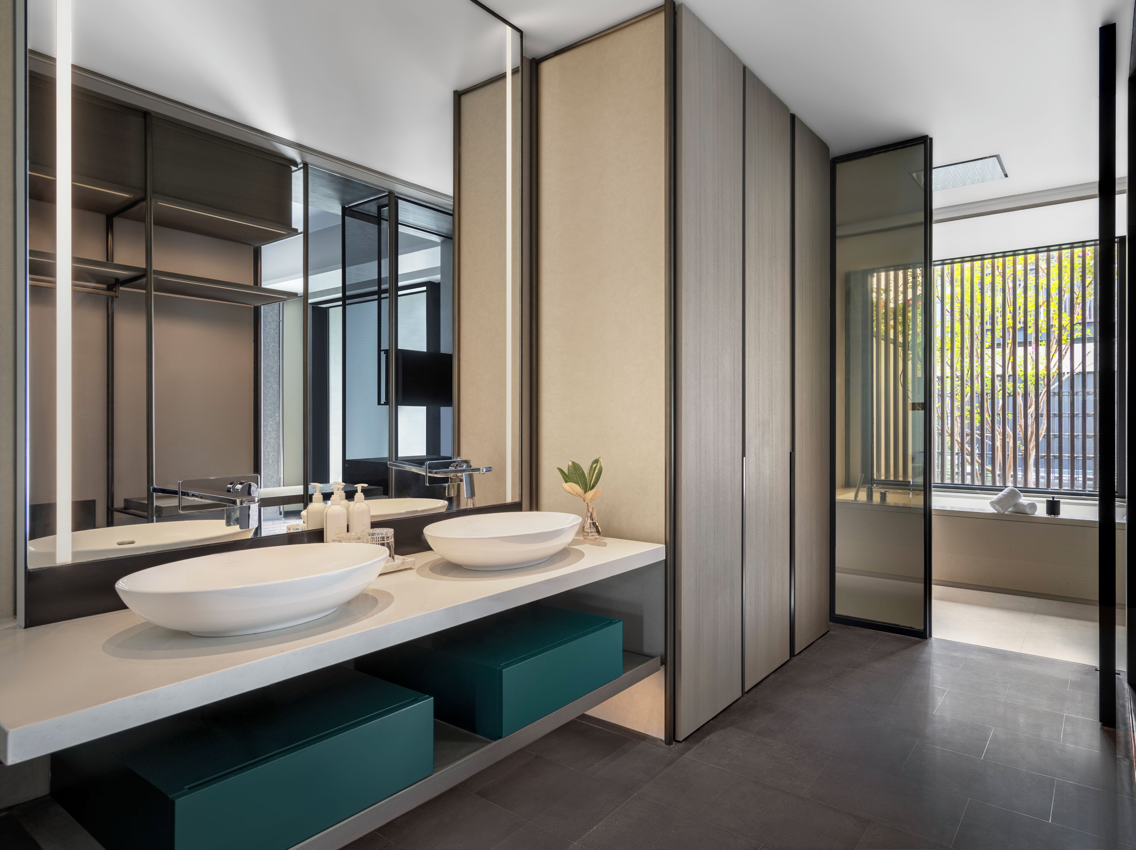 Un bagno moderno con due ampi lavabi bianchi, uno specchio e vista su un balcone con persiane verticali.