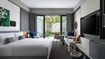 Een moderne hotelkamer met een groot bed, een televisie, een zithoek met een tafel en stoelen, en uitzicht op de omgeving.