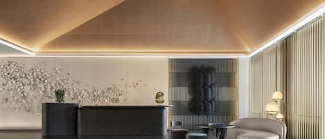 A modern lobby with a reception desk, seating area, and decorative wall panels.