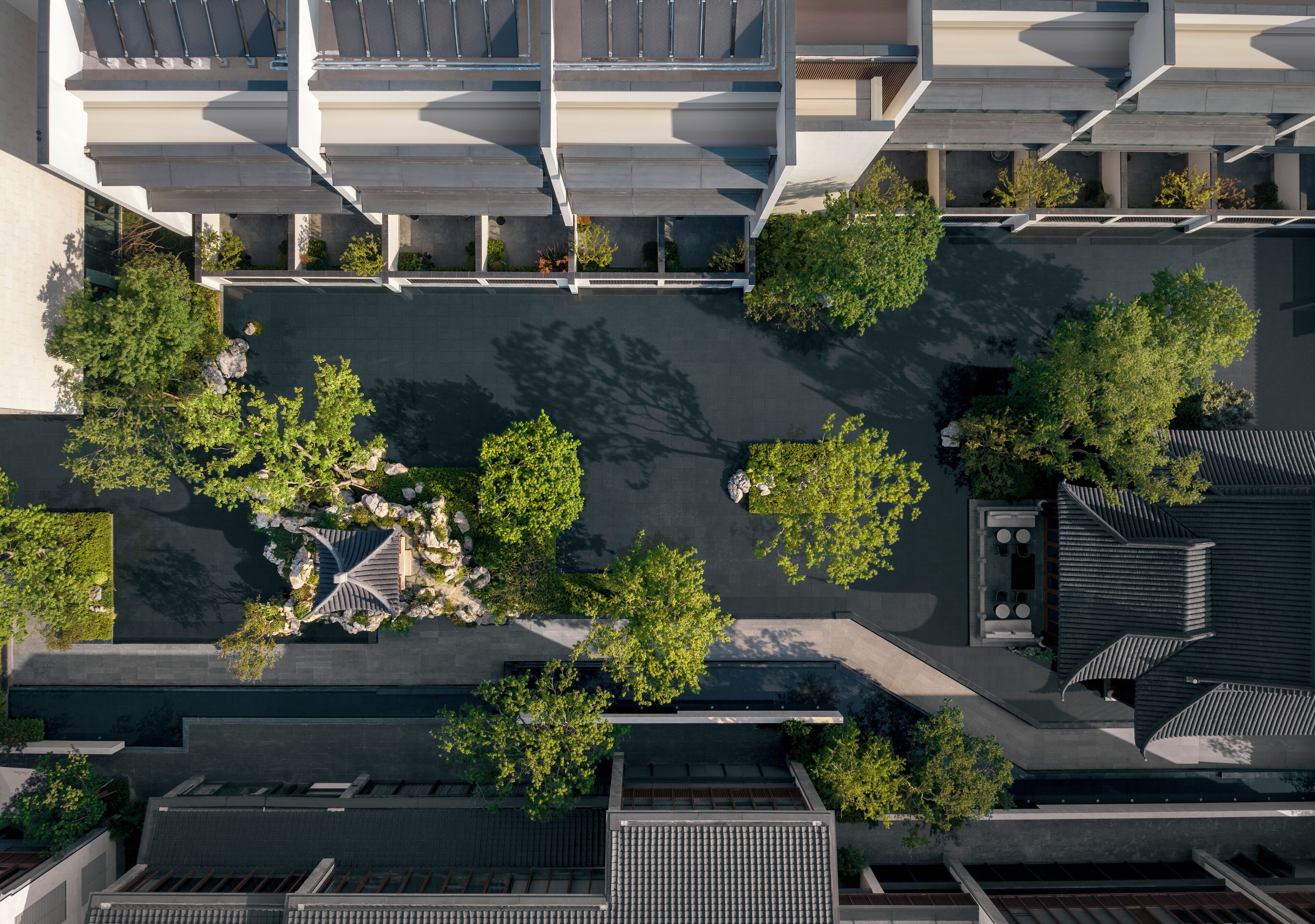 Vista aérea de un moderno complejo de edificios con varios niveles, pasarelas interconectadas y zonas verdes circundantes.